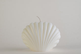 Shell Candle Ivory, candela a forma di conchiglia capasanta, vista frontale su fondo grigio chiaro
