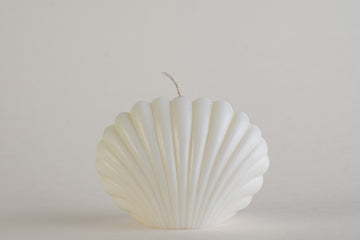 Shell Candle Ivory, candela a forma di conchiglia capasanta, vista frontale su fondo grigio chiaro