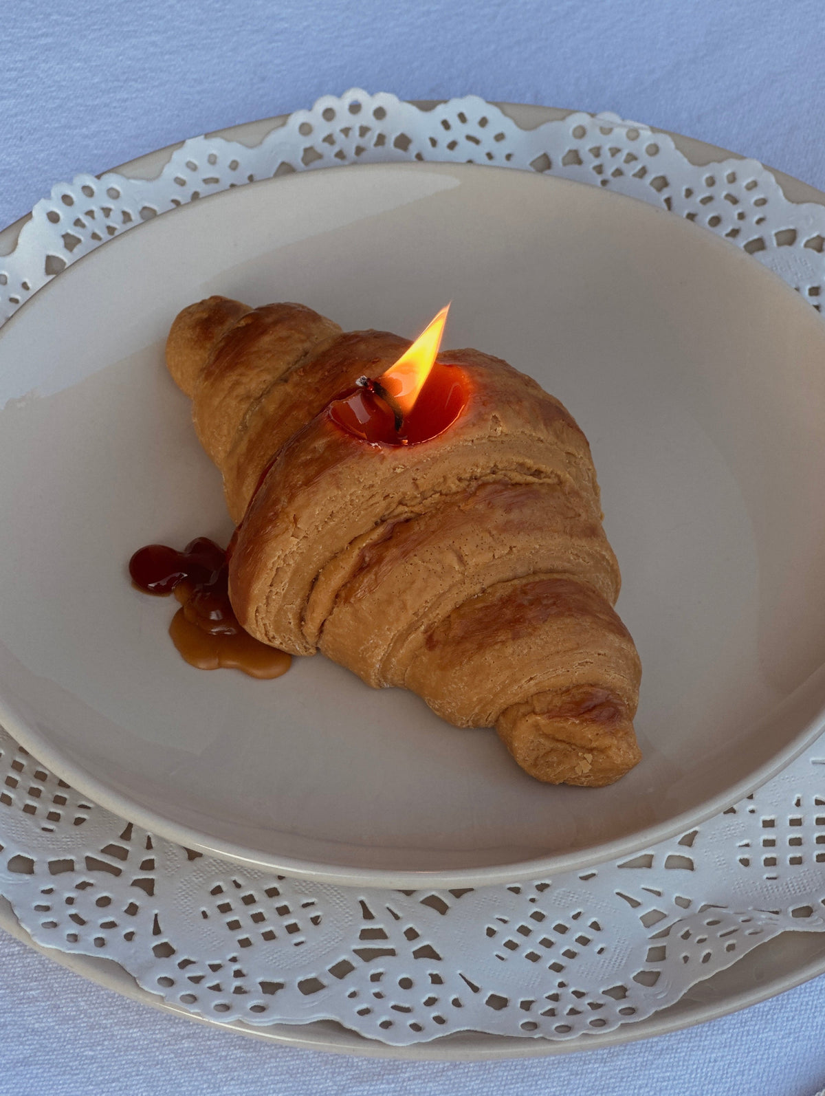 Candela a forma di croissant accesa su un piatto decorato.