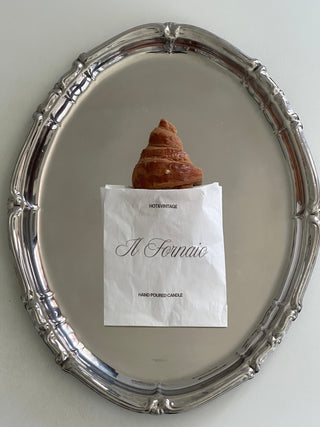 Candela a forma di croissant nel sacchetto personalizzato Il Fornaio, su un piatto argentato.
