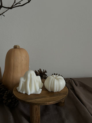 Candela di Halloween a forma di fantasma grande accanto a una zucca color avorio.