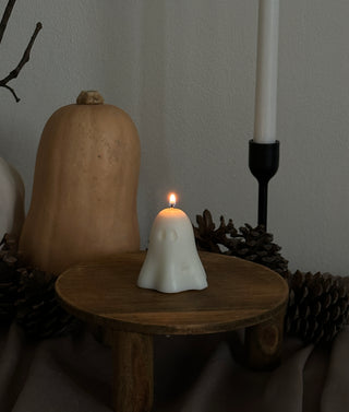 Candela di Halloween a forma di fantasma piccolo accesa su un tavolo con zucca e pinoli.