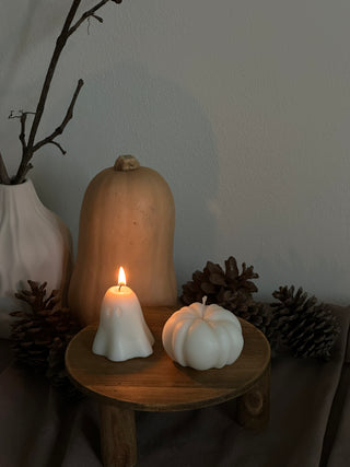 Candela di Halloween a forma di fantasma piccolo accanto a una zucca color avorio.