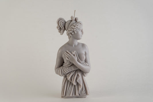 Candela scultorea Lady Aphrodite grigio pietra, raffigurata a figura intera con il busto leggermente ruotato, su sfondo chiaro.