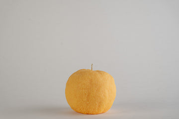 Lemon Candle, candela a forma di limone giallo con buccia in rilievo, vista frontale su fondo grigio chiaro
