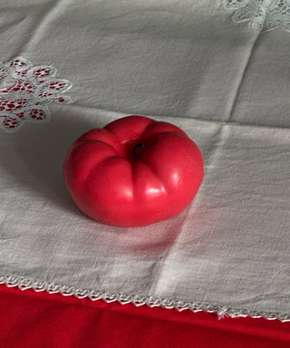 Candela a forma di pomodoro su una tovaglia a quadretti in cucina.