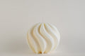 Big Spiral Ball Candle, candela sfera a spirale color avorio, vista frontale su fondo grigio chiaro