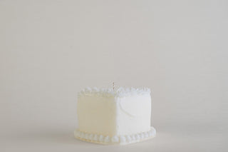 Candela a forma di torta a cuore Ivory con decorazioni a panna e bordo a perline, su sfondo chiaro