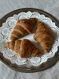 Tre candele a forma di croissant disposte su un piatto decorato.