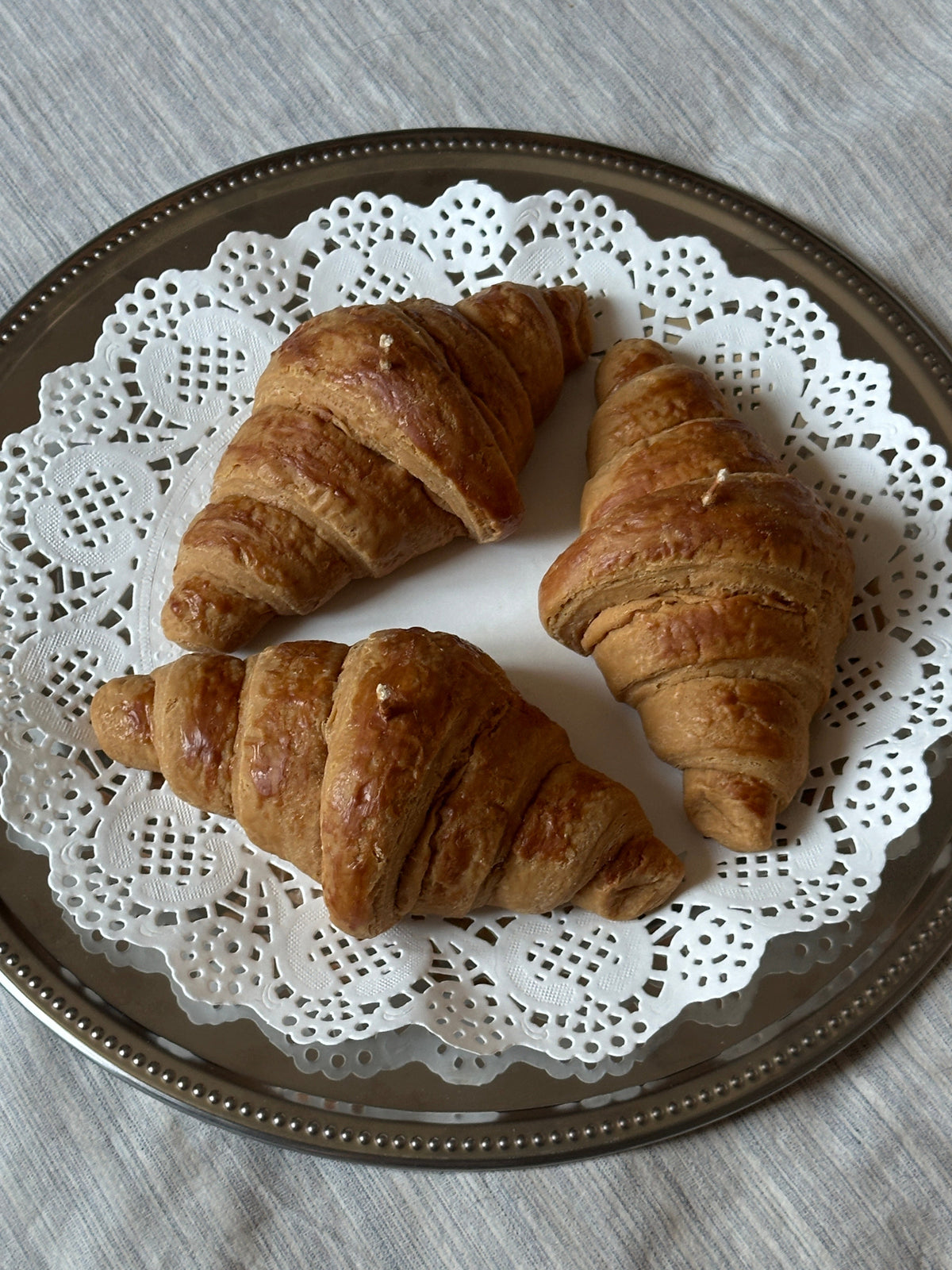 Tre candele a forma di croissant disposte su un piatto decorato.
