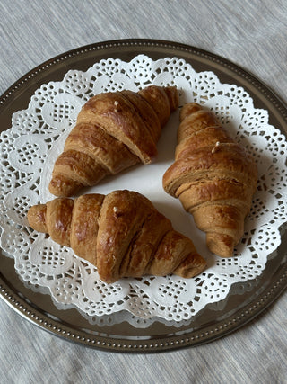Tre candele a forma di croissant disposte su un piatto decorato.