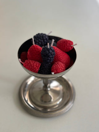 Candele a forma di frutti di bosco raccolte in una coppetta argentata.