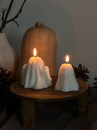 Candele di Halloween a forma di fantasma grande e piccolo, con una zucca sullo sfondo.