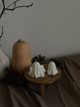 Candele a forma di fantasma e zucca con pinoli, fotografate dall’alto su un tavolo di legno con tovaglia marrone.