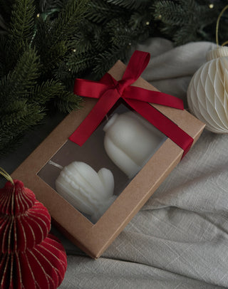 Candele a forma di maglione e muffola nella scatola con finestra trasparente e fiocco rosso.