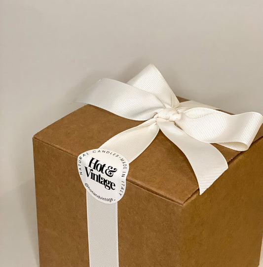 Scatola regalo color kraft con nastro e fiocco bianco, pronta da donare.