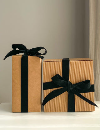 Scatola regalo color kraft con nastro e fiocco nero, pronta da donare.