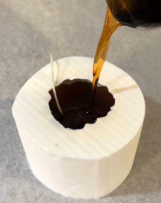Colata della cera nello stampo bianco per la candela a forma di zucca Hot&Vintage, con lo stoppino già posizionato