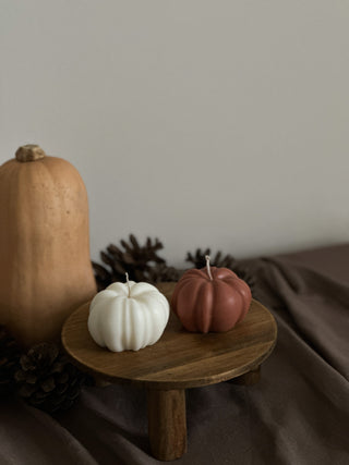Tre candele di Halloween a forma di zucca color avorio su un tavolo di legno.