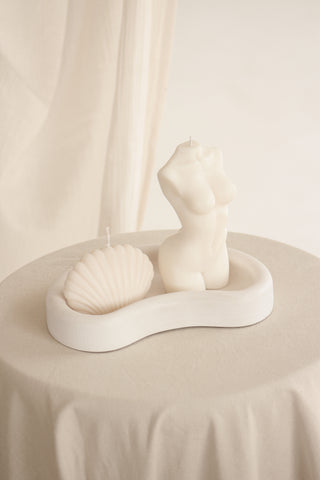 Vassoio Mezzaluna in Jesmonite decorato con una conchiglia e le candele scultoree Venus e Lady Aphrodite.
