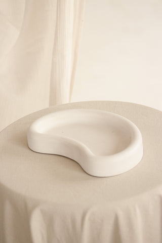 Vassoio Mezzaluna in Jesmonite ripreso frontalmente su una tavola rotonda coperta da una tovaglia chiara.
