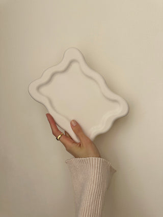 Vassoio quadrato dai bordi ondulati tenuto in mano.